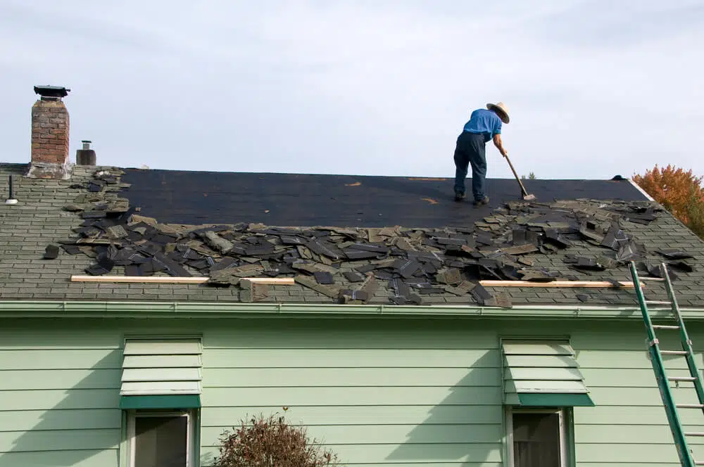 man on roof replacing shingles