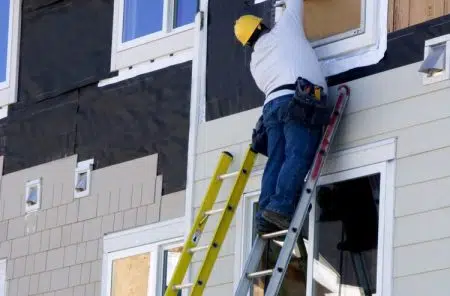 man installing siding on a home