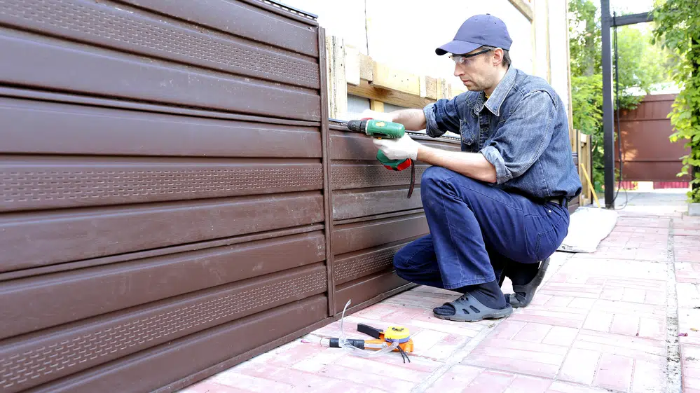 Worker installs plastic siding on the facade of the building