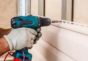 man screwing siding in a home