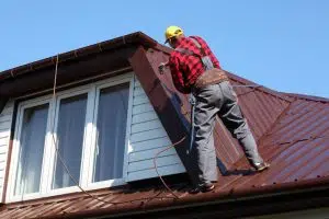 worker spraying paint on a metal sheet roof