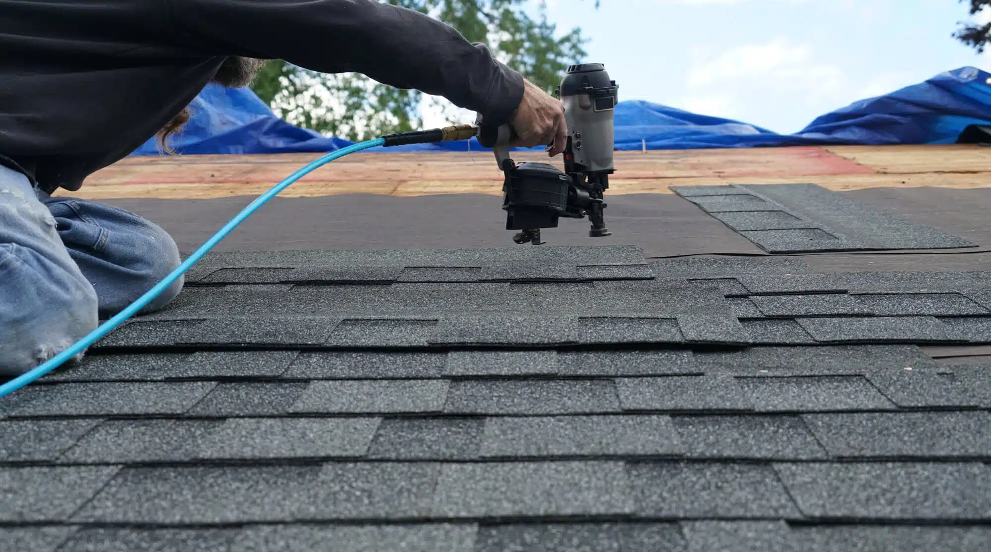 man working on the roof using a hand tool