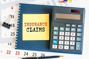 yellow not with roof insurance claims written on it, a calculator beside it.