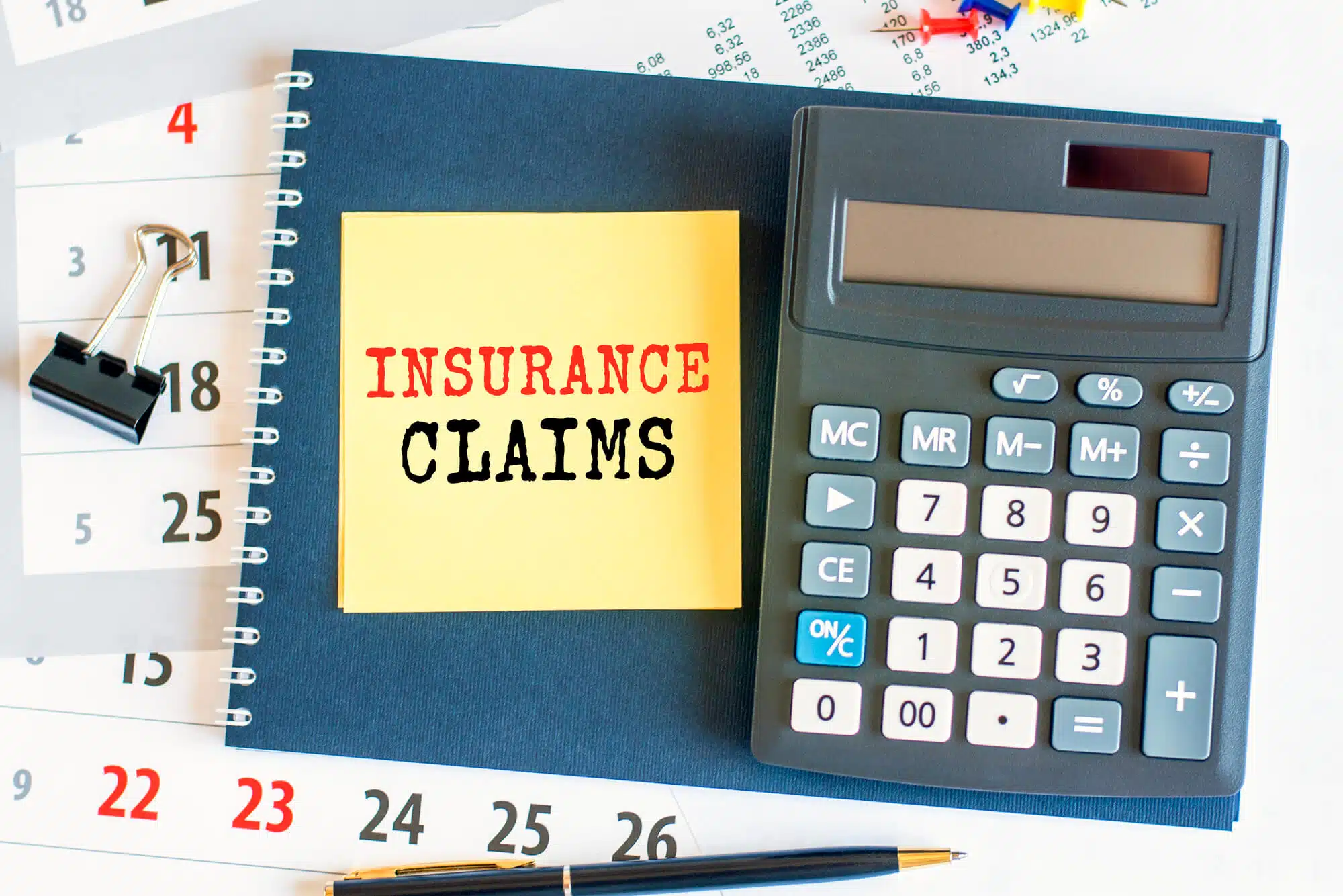 yellow not with roof insurance claims written on it, a calculator beside it.