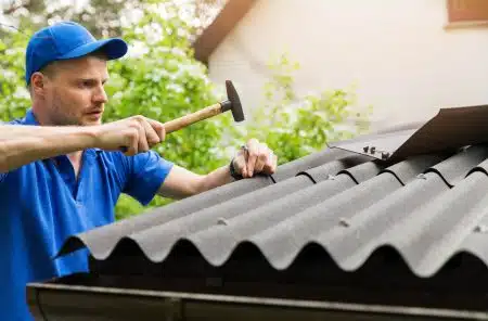 man hammering nail on a roof